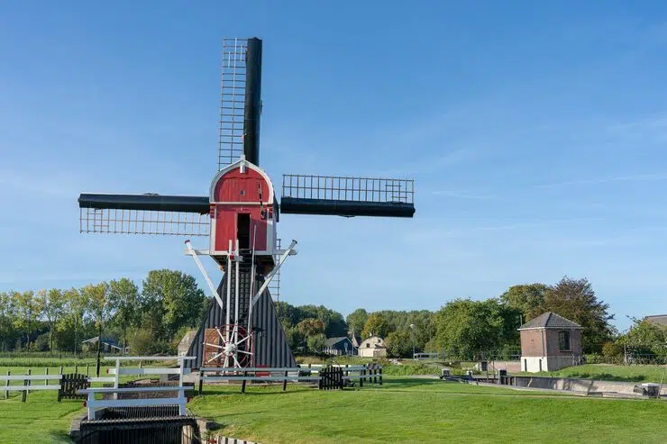 Windmill surrounded by trees under clear sky near Assendelft